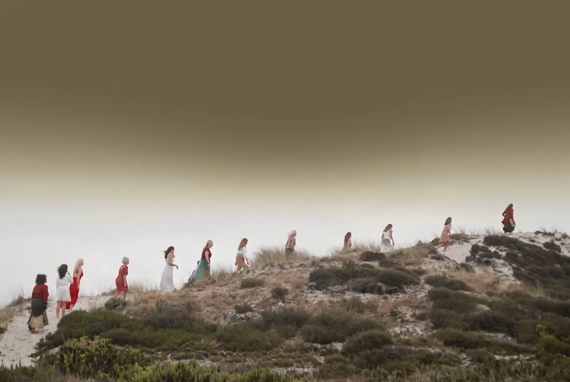 Women walking together across a dune at dusk